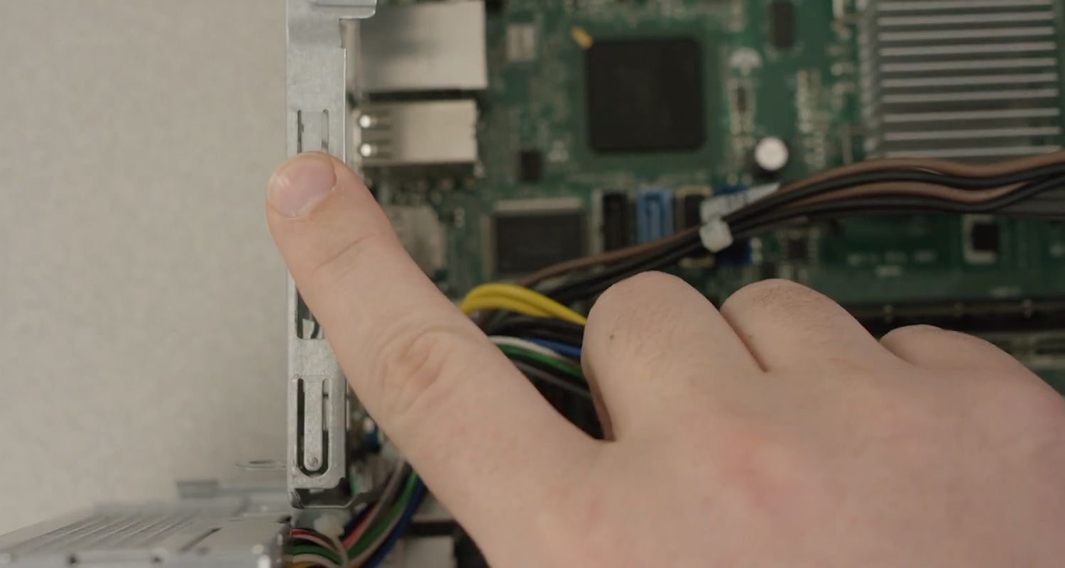Finger touching an unpainted metal surface in the interior of a desktop PC to discharge static charge